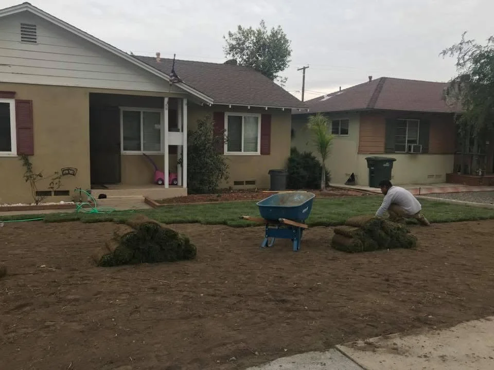 Bare soil yard with sod removal debris and preparation work in progress at residential home