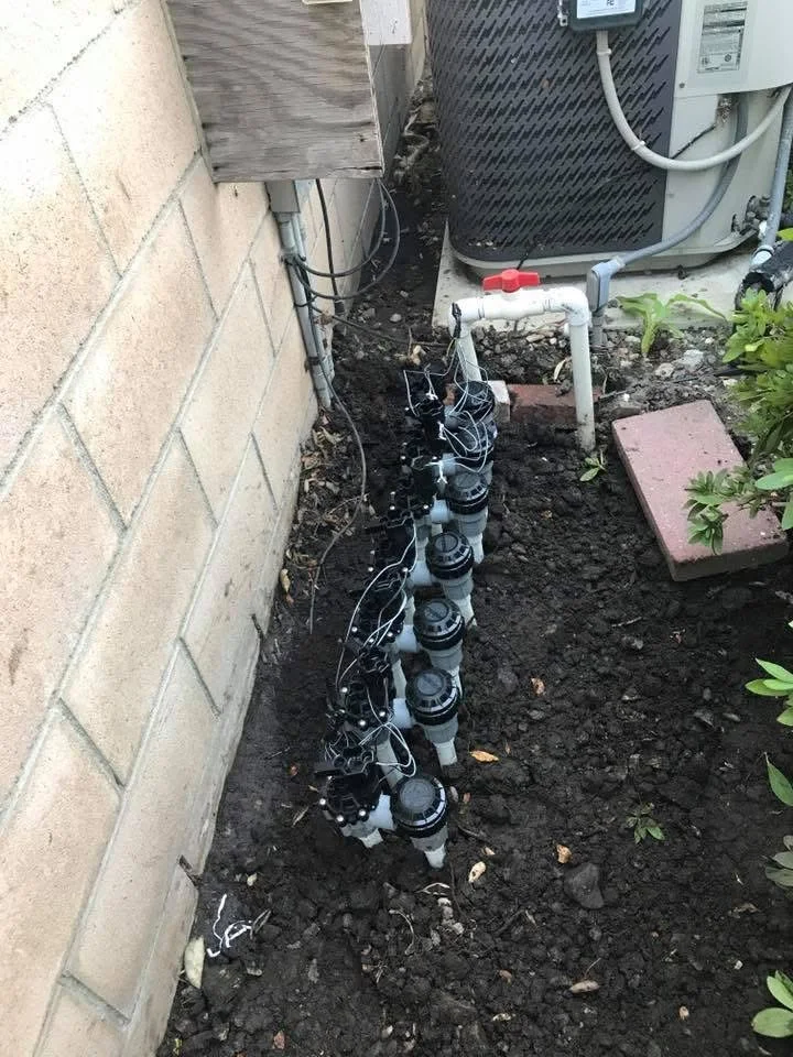Underground irrigation system with valve boxes and PVC piping along foundation